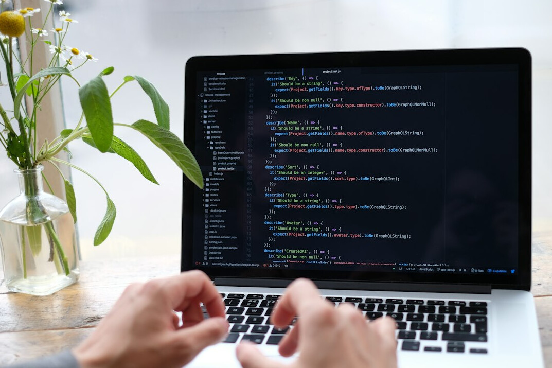 person writing code on laptop
